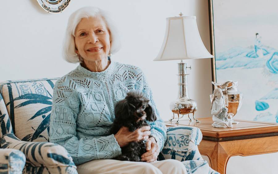 Barbara Smith at home sitting with her small black dog.